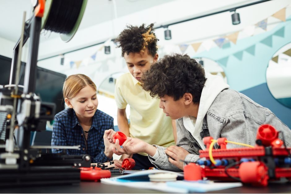 An image of three middle-school aged kids engineering battle bots for a stem program.